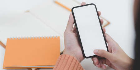 Close-up view of young female holding blank screen smartphone in comfortable office room の写真素材