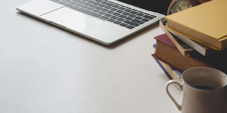 Cropped shot of modern workspace with laptop computer and books on white table background with coffee cupの写真素材