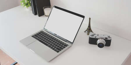 Minimal photographer workspace with open blank screen laptop computer with vintage camera and office suppliesの写真素材