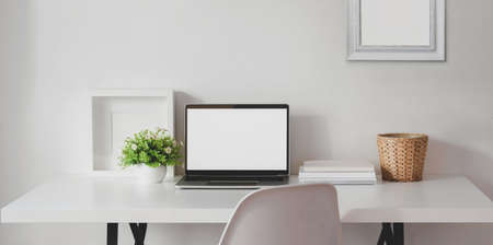 Minimal workspace with open blank screen laptop computer with mock up frame and office supplies の写真素材