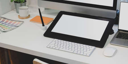 Close-up view of designer workplace with blank screen digital tablet with desktop computer with office supplies の写真素材