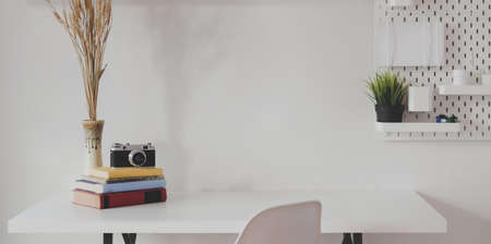 Minimal photographer workspace with vintage camera and office supplies with white wall background の写真素材