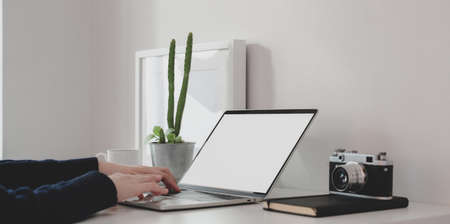 Close-up view of young female working on her project while typing on blank screen laptop computer in modern workplaceの写真素材