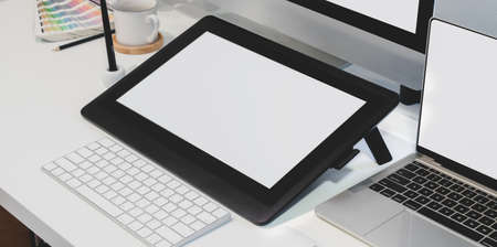 Close-up view of designer workplace with blank screen digital tablet with desktop computer with office supplies の写真素材