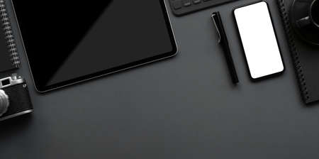 Top view of dark luxury workspace with copy space, blank screen smartphone, keyboard and office supplies on grey background の写真素材
