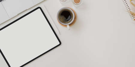 Top view of autumn workspace with blank screen tablet, coffee cup and office supplies on white desk table の写真素材