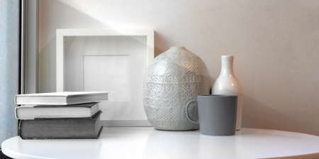 Ceramic vases and mock up frame on white table in minimal workspace next to the windows の写真素材