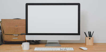 Mock up desktop computer in modern home-office room with office supplies and mailbag on wooden table の写真素材