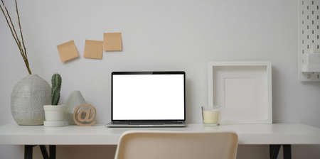 Minimal workspace with blank screen laptop computer with mock up frame and decorations with copy space の写真素材