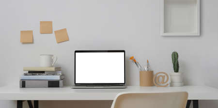 Open blank screen laptop computer in minimal workplace with painting tools and office supplies の写真素材