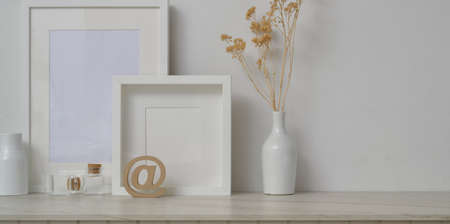 Minimal workspace with mock up frames and decorations in white wall background and white desk の写真素材