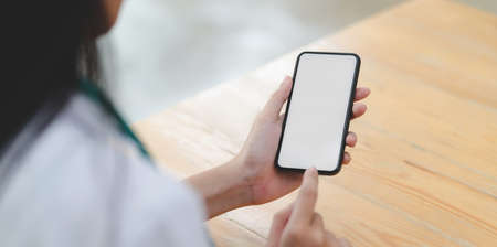 Close-up view of young female doctor touching blank screen smartphone in her office room の写真素材