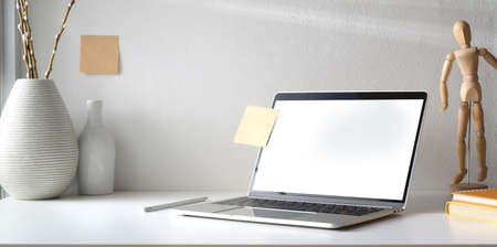 Minimal workspace with open blank screen laptop computer and coffee cup with ceramic vase decorations の写真素材