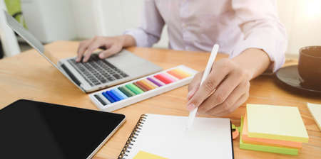 Cropped shot of young professional designer planing his project while using laptop computer の写真素材