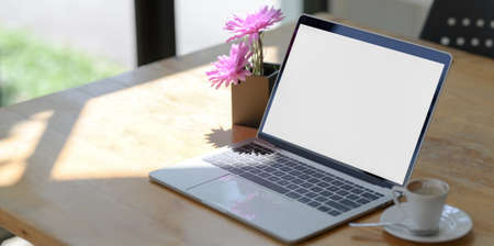 Open blank screen laptop computer in comfortable workspace next to the windows with coffee cup の写真素材