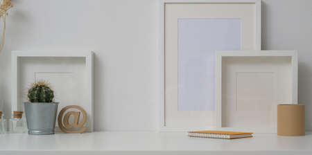 Minimal workspace with mock up frames and decorations in white wall background and white table の写真素材