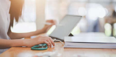 Close-up view of female doctor summarise her patient chart on digital tabletの写真素材