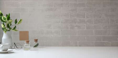 Minimal workspace with copy space and office supplies on white desk and grey brick wall backgroundの写真素材