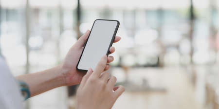 Cropped shot of young female professional doctor using her smartphone in workspace の写真素材