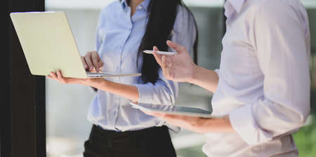 Cropped shot of group of professional businesspeople discussing their current project together while using tabletの写真素材