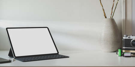 Mock up tablet in minimal workspace with copy space and ceramic vase decorations の写真素材