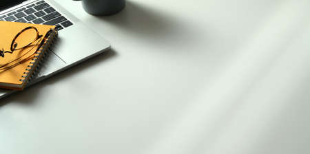 Cropped shot of modern workplace wit laptop computer, books and office supplies with copy space on white desk backgroundの写真素材