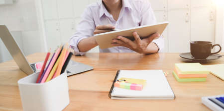 Close-up view of young male designer planing his project while tablet in his workplaceの写真素材