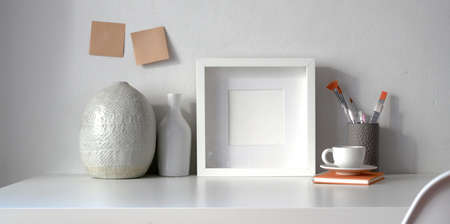 Minimal workspace with mock up frame and copy space with ceramic vase decorations on white table の写真素材