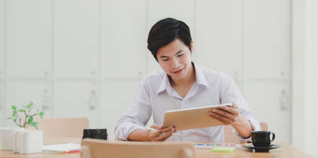 Young professional male designer planing his project with tablet in his workplaceの写真素材