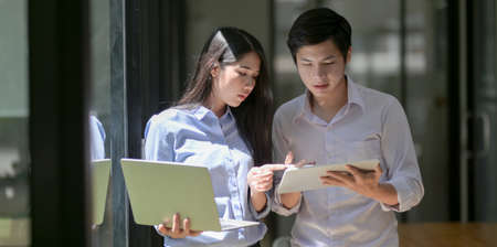 Portrait of young professional business partner discussing their project together in modern office roomの写真素材