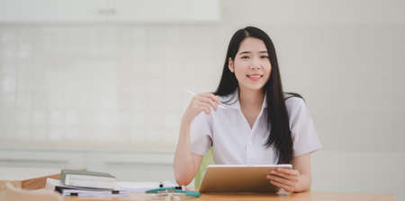 Portrait of beautiful young female doctor examining the patient chart and smiling to the cameraの写真素材