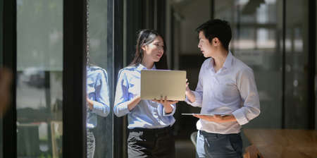 Two young professional business partner discussing their project together in modern office roomの写真素材