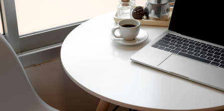 Open blank screen laptop computer in modern workspace with coffee cup and office supplies の写真素材