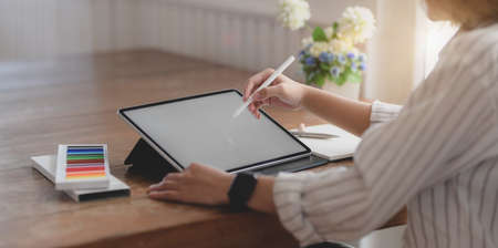 Cropped shot of young professional designer drawing on her project with blank screen tablet in comfortable workspaceの写真素材