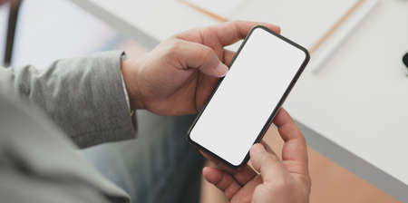 Close-up view of professional businessman holding blank screen smartphone in his office roomの写真素材