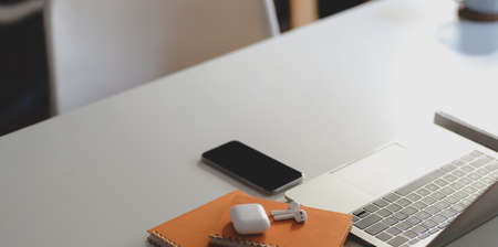 Close-up view of modern workplace with smartphone and office supplies on white wooden table の写真素材