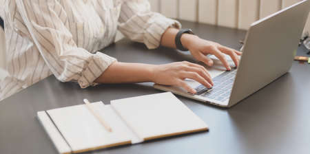 Close-up view of young beautiful businesswoman typing on laptop computer in comfortable workplace