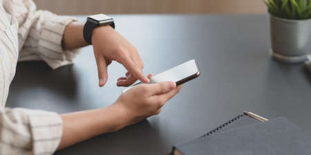 Close-up view of young professional businesswoman touching blank screen smartphone in her office roomの写真素材