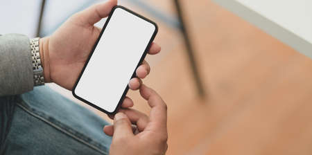 Close-up view of professional businessman holding blank screen smartphone in his office roomの写真素材