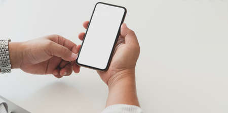 Close-up view of professional businessman holding blank screen smartphone in his office roomの写真素材