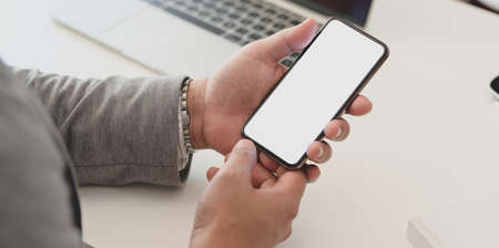Close-up view of professional businessman holding blank screen smartphone in his office roomの写真素材