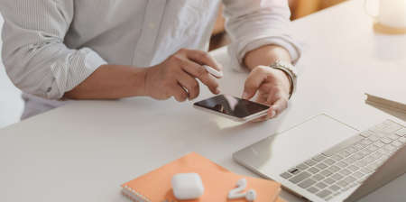 Close-up view of businessman looking for information on smartphone while working on the project