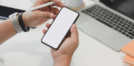 Close-up view of businessman surfing the internet on blank screen smartphone in his office roomの写真素材
