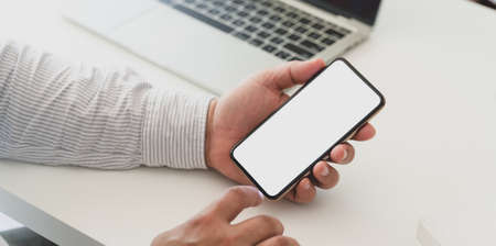 Close-up view of professional businessman holding blank screen smartphone in his office roomの写真素材