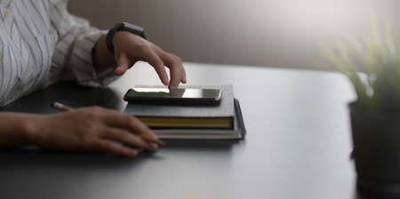 Cropped shot of young businesswoman working on her current project while touching smartphone in workspaceの写真素材