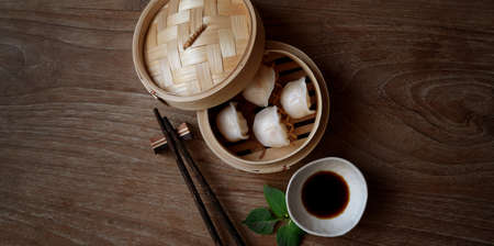 Overhead shot of Chinese steamed dumpling in a bamboo steamer with chopstick on wooden table and copy spaceの写真素材