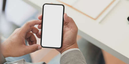 Close-up view of professional businessman holding blank screen smartphone in his office roomの写真素材