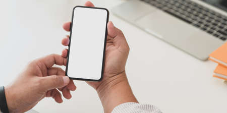 Close-up view of businessman surfing the internet on blank screen smartphone in his office roomの写真素材