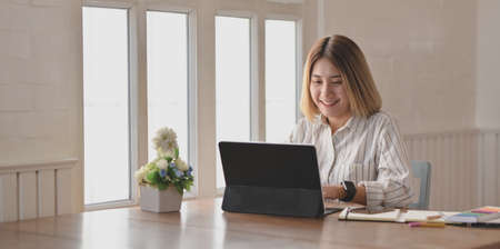 Young beautiful businesswoman working on her project with smartphone in comfortable workplaceの写真素材
