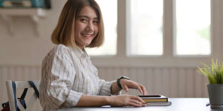 Young beautiful businesswoman working on her project with smartphone in comfortable workplaceの写真素材